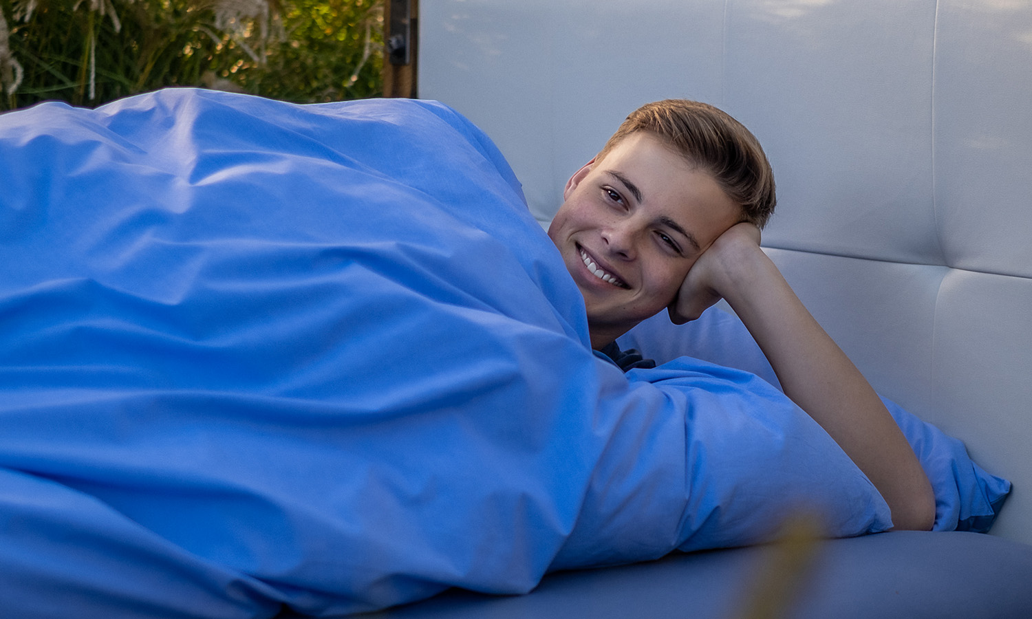 Junger Mann lächelt im Bett